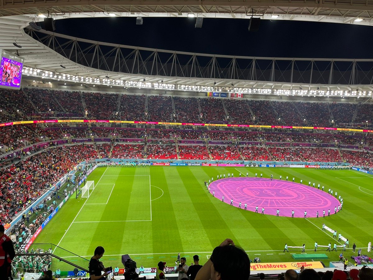 A view from pitch level at Ahmad Bin Ali Stadium, showing players and staff during warm-up