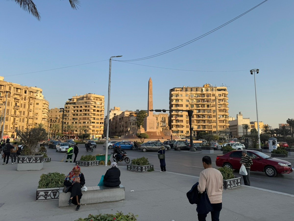 Bustling Mansheya Square with historic buildings and an obelisk in Alexandria, Egypt.