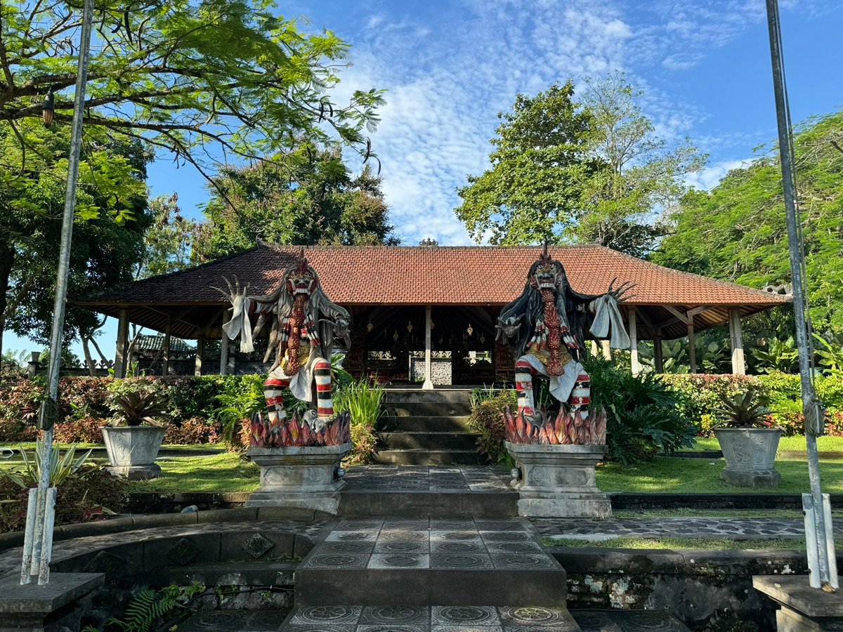 Wider view of Tirta Gangga water palace with pathway, ponds, and distant traditional pavilion