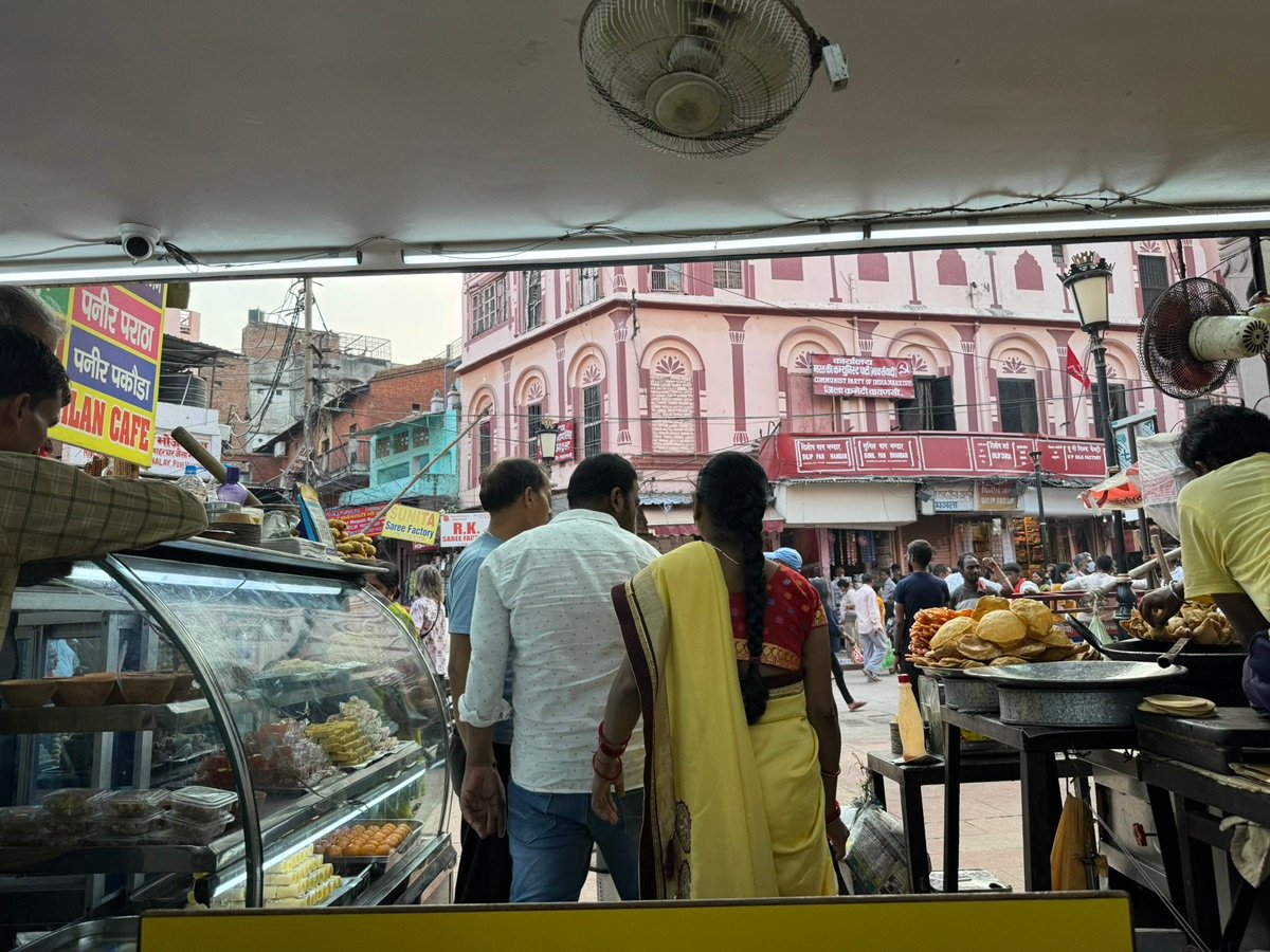 バラナシの屋台で食べ物を見ている黄色いサリーの女性。