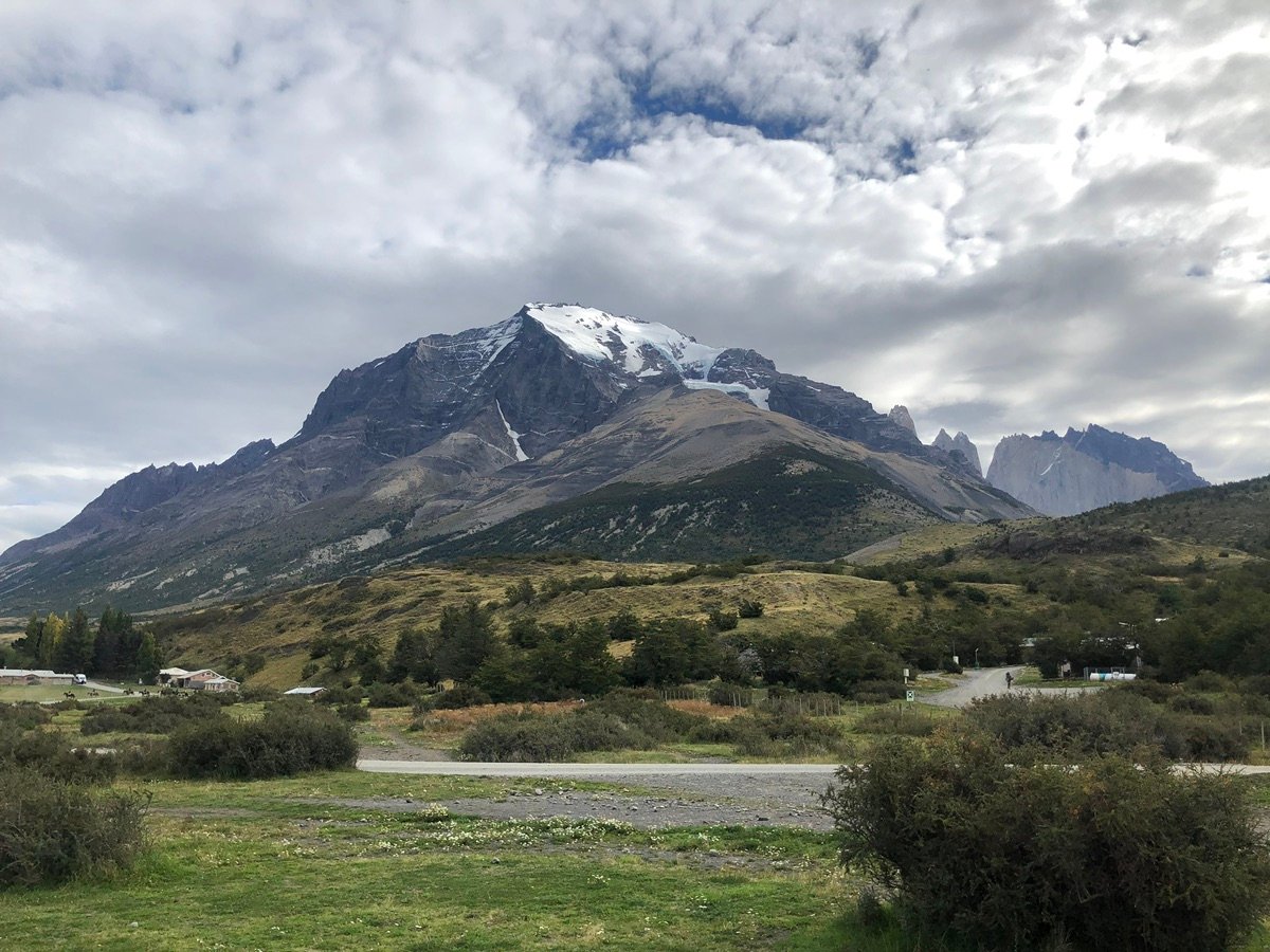 在多云的天空下,穿过草地通往山脉的蜿蜒土路。