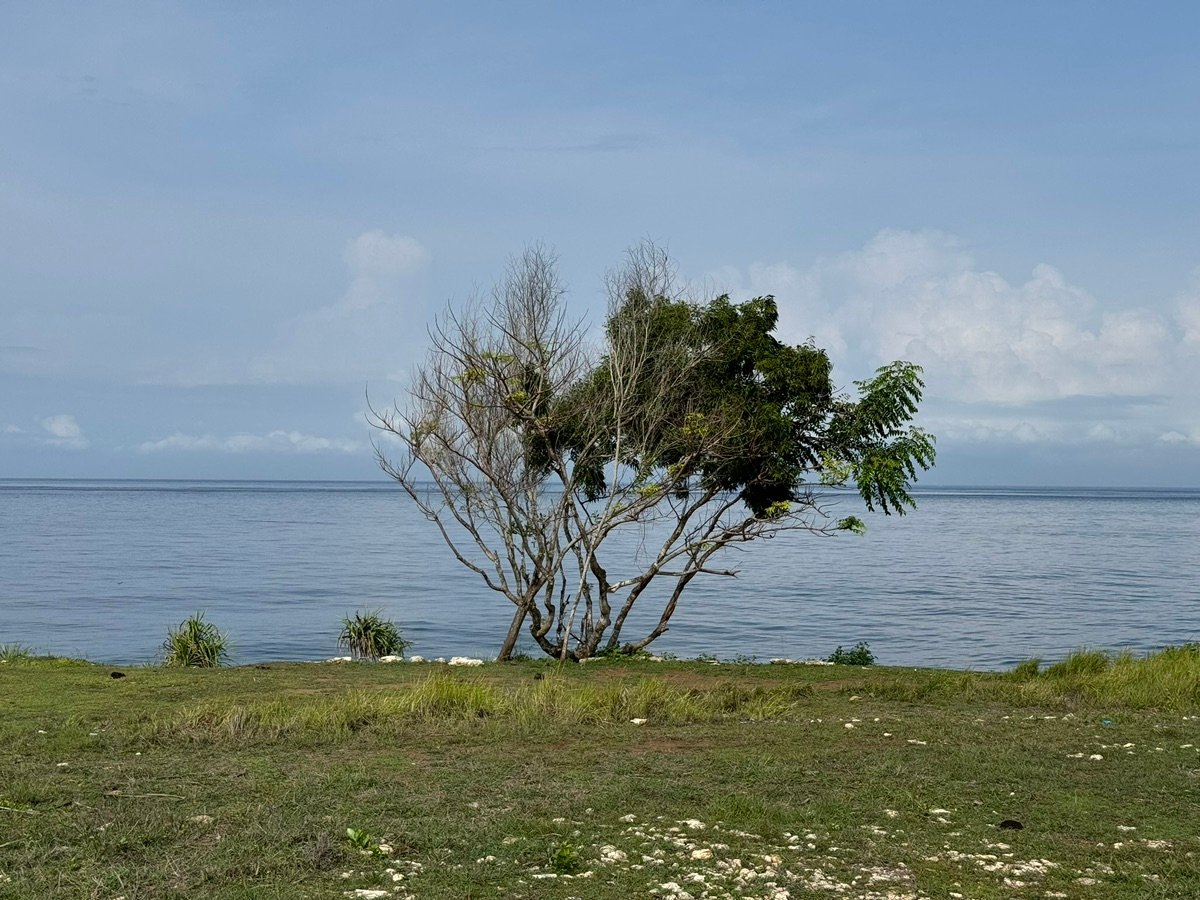 Rocky beach and turquoise waves at Tegal Wangi Beach under a cloudy sky