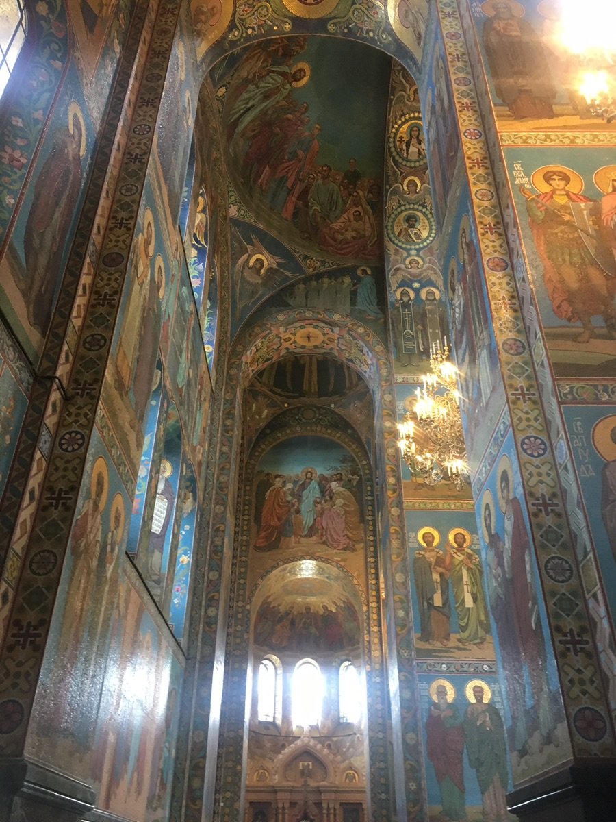 Spacious mosaic-covered interior of the church with glowing chandeliers