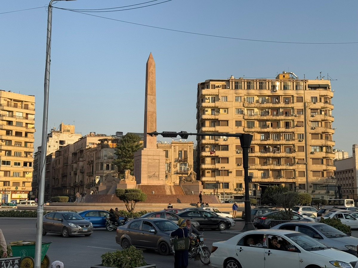 A broader view of Mansheya Square, showing the obelisk, buildings, and busy road with cars.