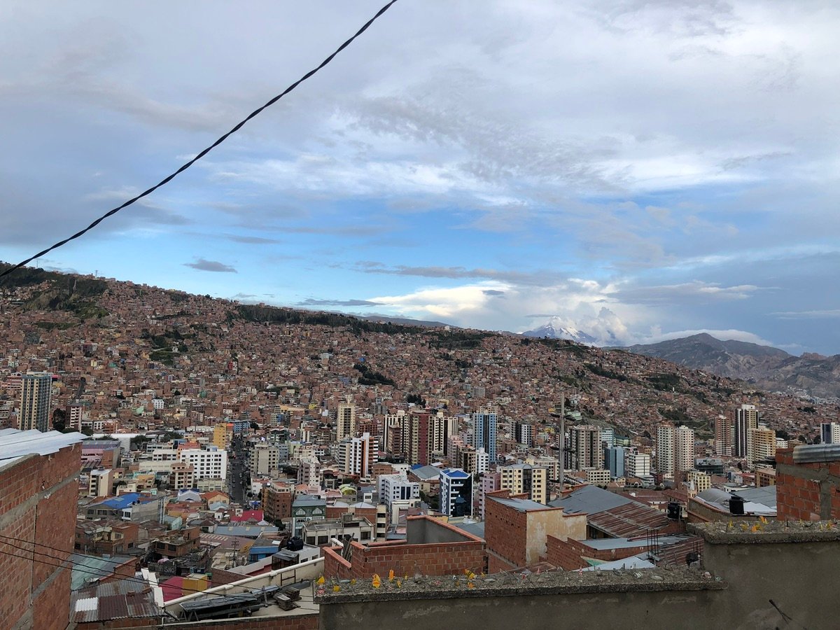 The snow-capped peak of Mount Illimani in the distance amidst clouds