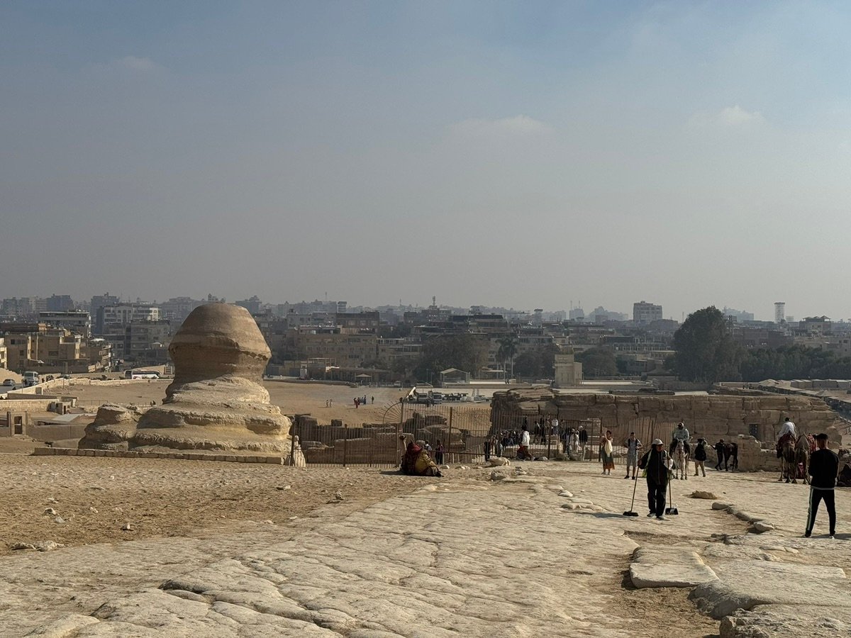 从高处俯瞰吉萨狮身人面像和吉萨城市全景,可见骆驼和游客