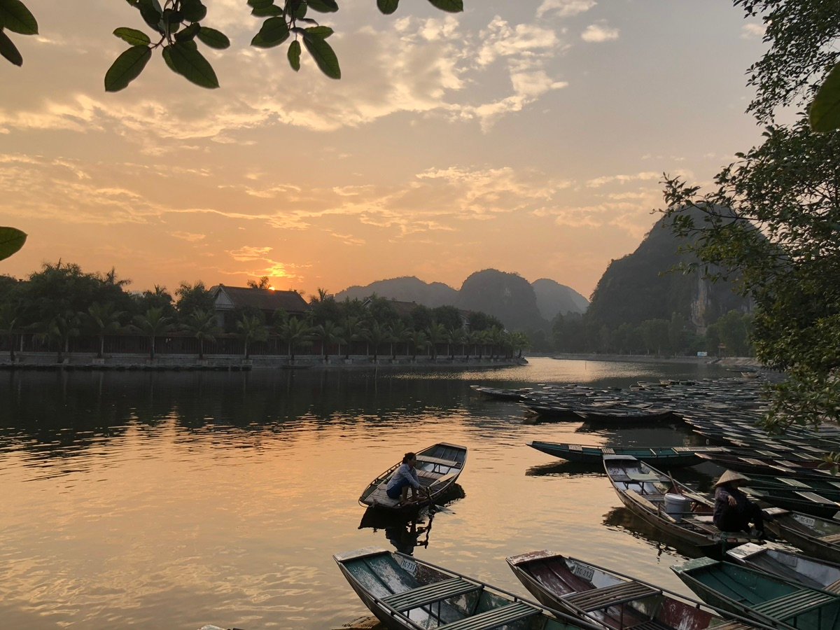 People rowing boats on Tam Coc river at sunset