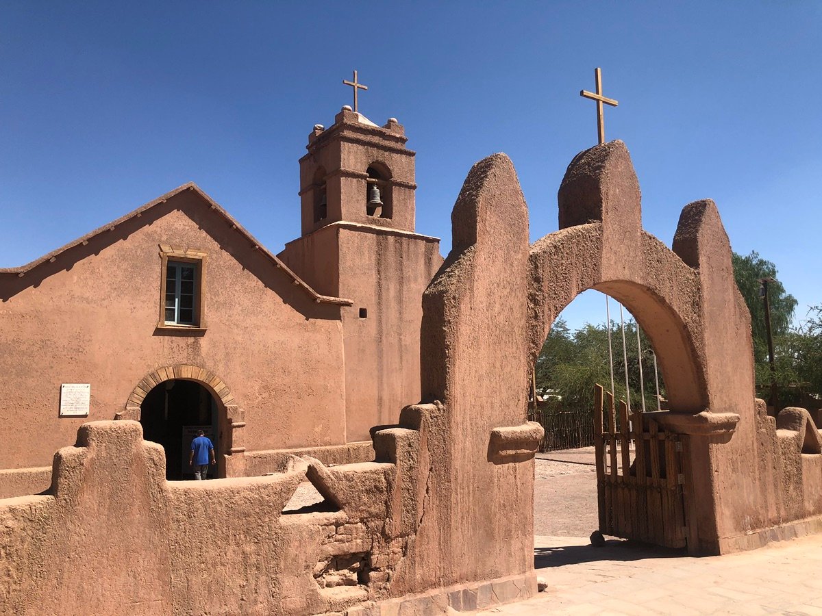 The arched entrance gate of the San Pedro de Atacama Church with a wooden gate.