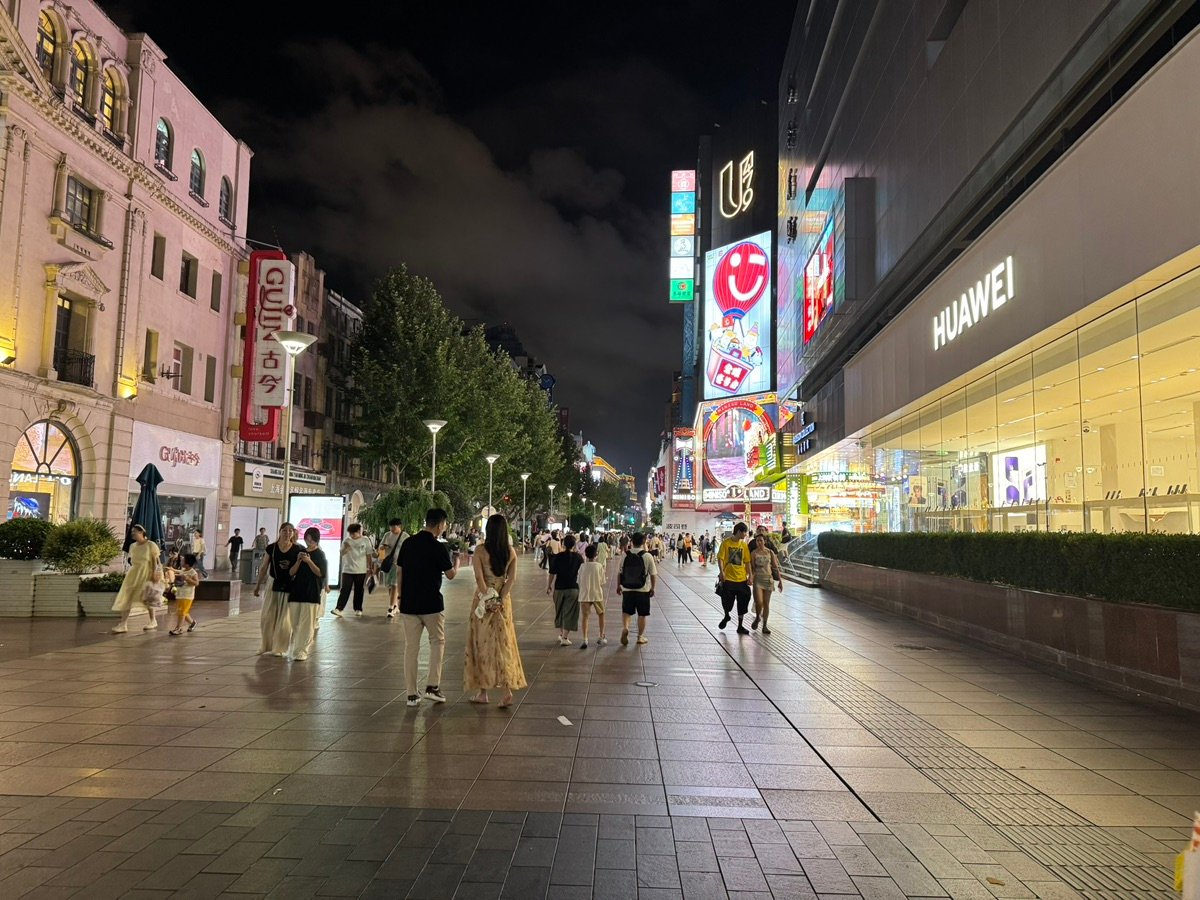 Crowds of people strolling along Nanjing Road Pedestrian Street at night