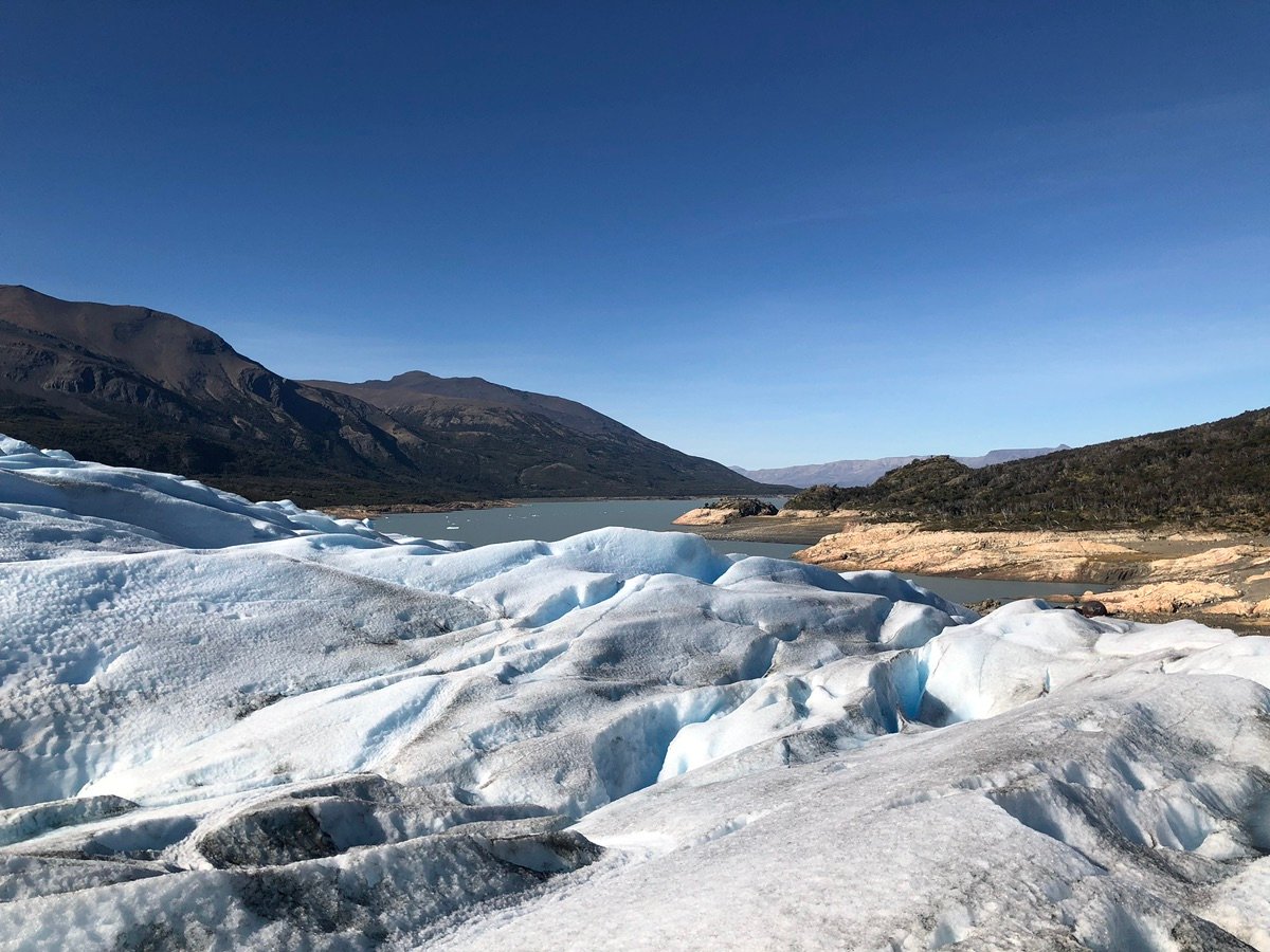 蓝天下，冰川起伏的表面和远处的群山