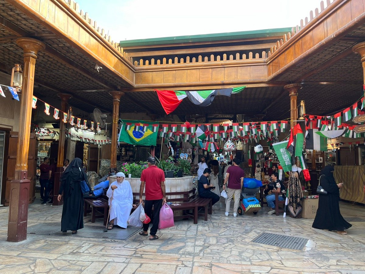 アル・シーフ・スークの広い通路の眺め。店が並び、人がカートを押しており、市場の賑わいを強調しています。