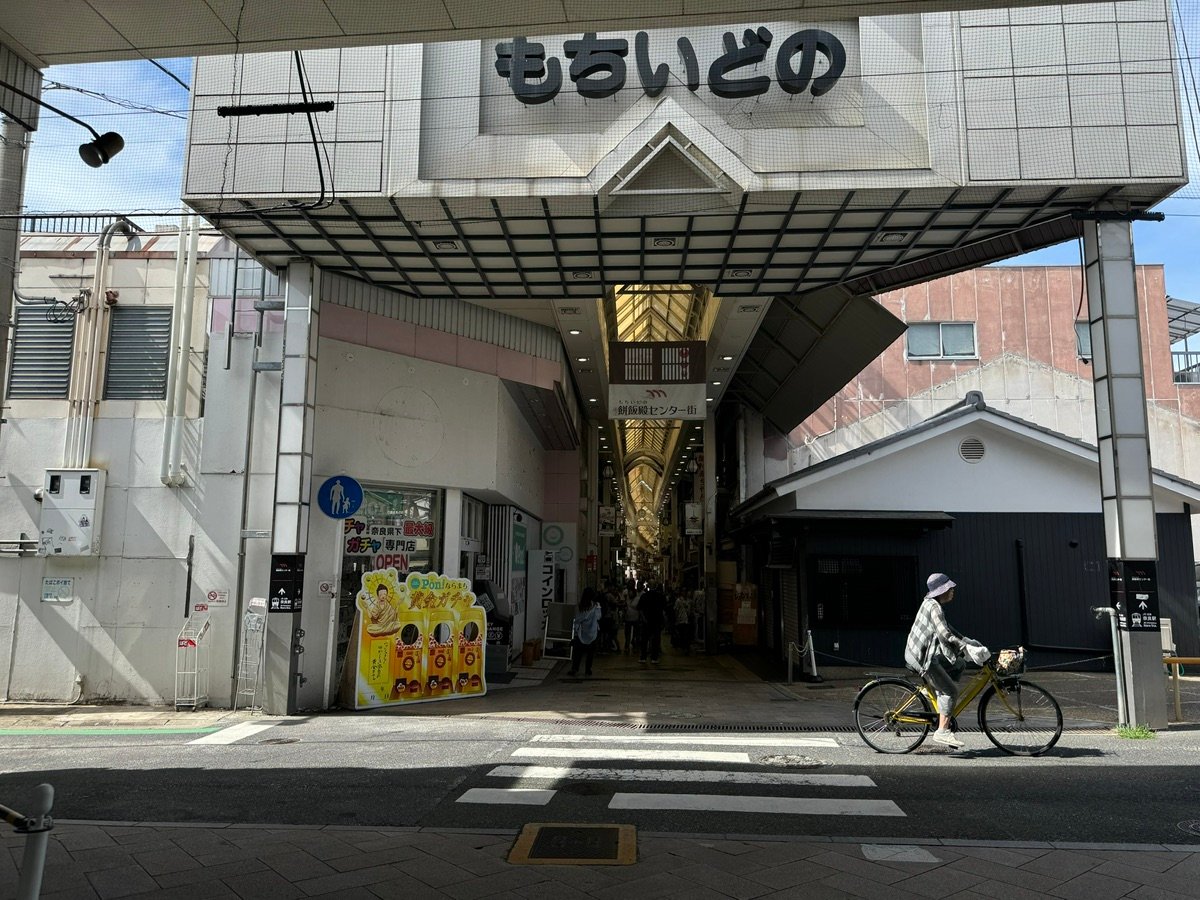 A cyclist rides past the entrance of Mochiidono Shopping Street in Nara.