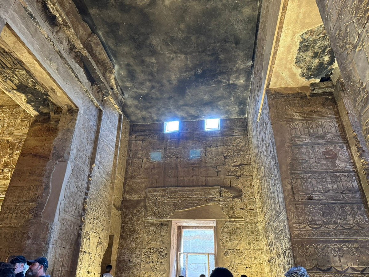 Light filters through small windows onto the carved walls of Edfu Temple.
