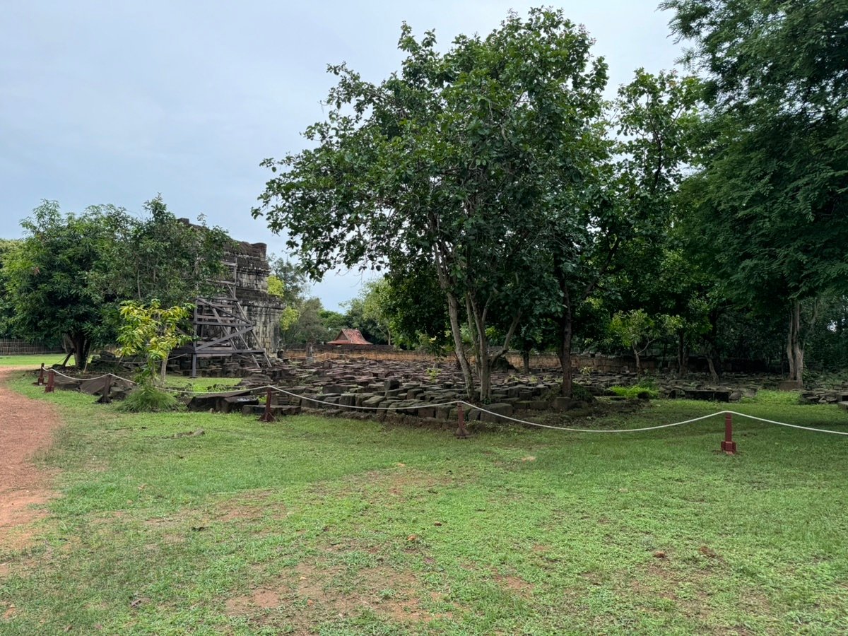 Ruinas antiguas y piedras dispersas rodeadas de árboles verdes en Phnom Bakheng.