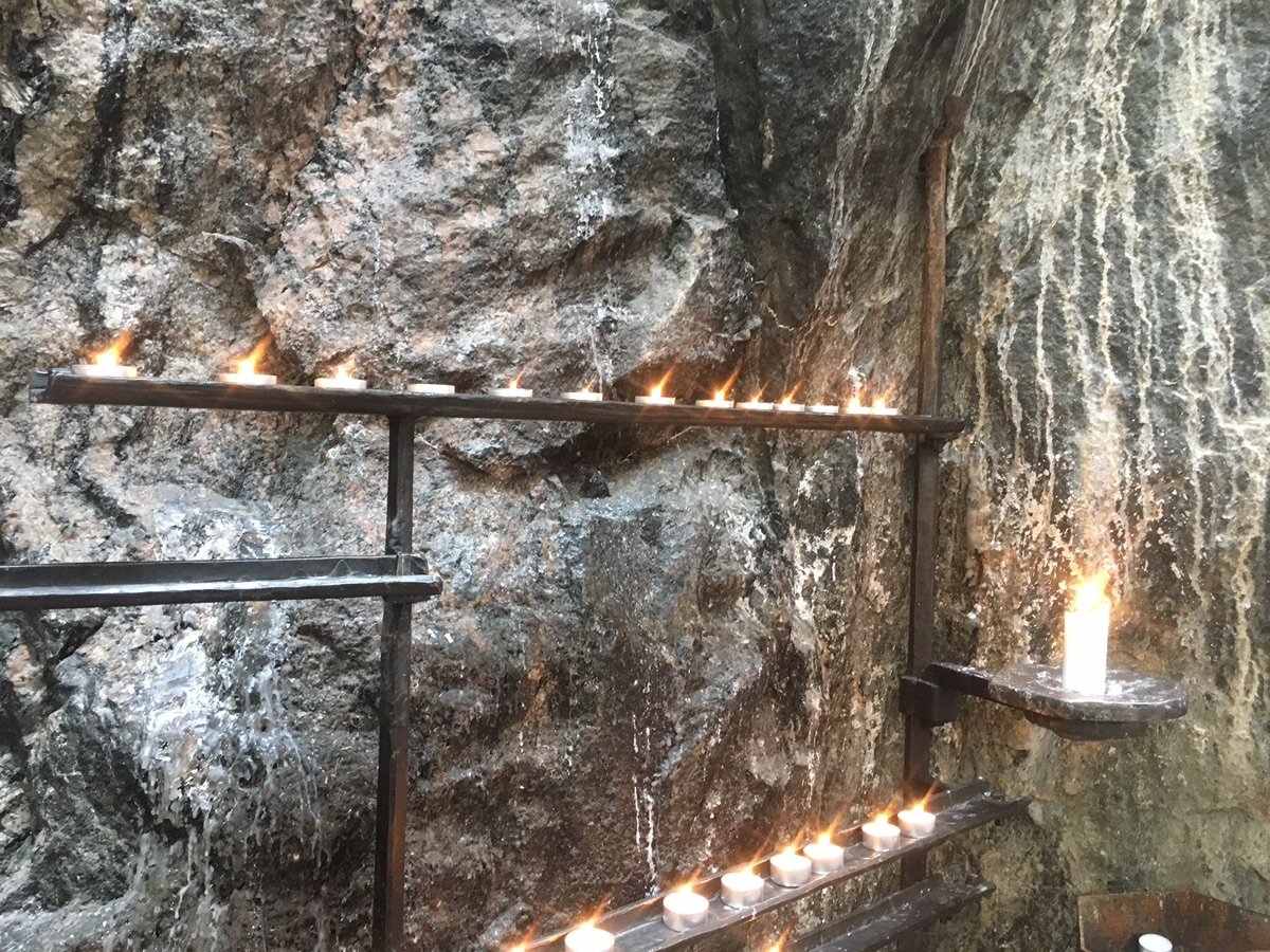 Candles glow against the rugged stone wall inside Helsinki's Rock Church.