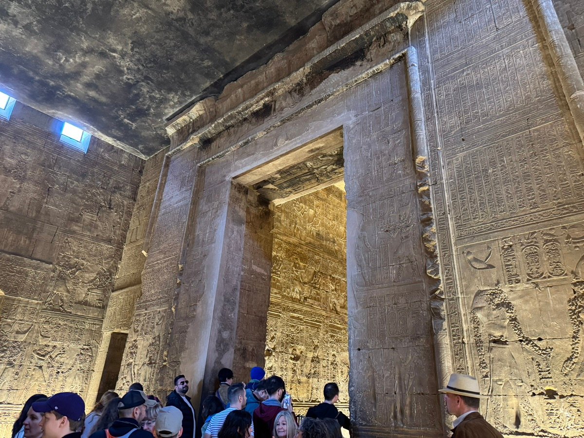 People admiring the ancient hieroglyphs carved into the Temple of Edfu.