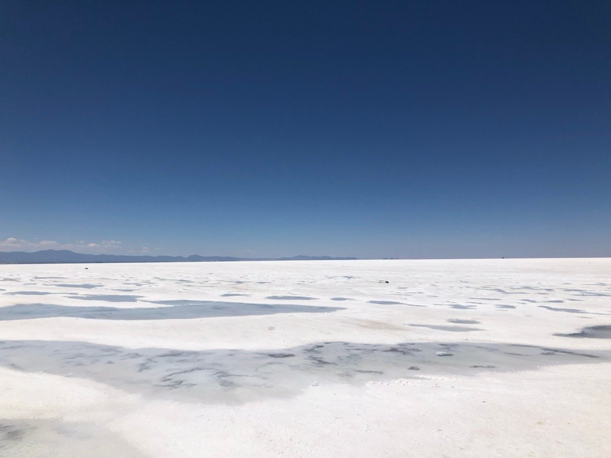 The white salt flats of Salar de Uyuni in Bolivia under a clear blue sky.